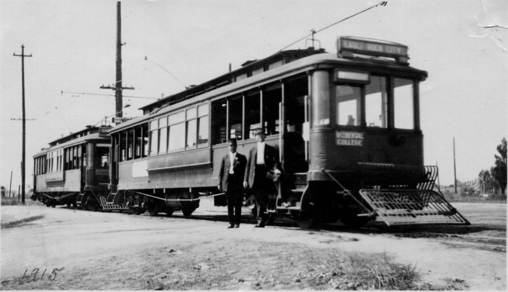 The Conductor and Motorman pose at an unknown stop in 1915. Note the Occidental College destination sign. The area around the dirt boulevard seems quite undeveloped. (ERVHS)