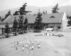 The May Festival was the second of the two yearly community festivals sponsored by the PTA. In those days when few women worked, the PTA was the focus of many women’s efforts. Often the organization had over one hundred members and raised substantial funds to enhance the schools. The children celebrate in 1930.The rear of the 1917 building stands in the background, with the auditorium wing projecting to the right. The playground has been paved. -ERVHS